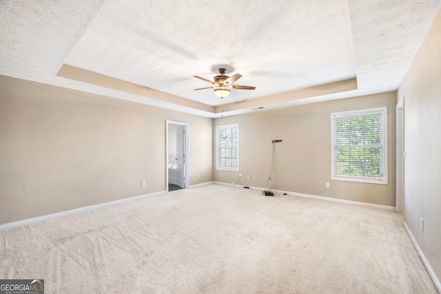 carpeted spare room featuring ceiling fan, a raised ceiling, and a textured ceiling