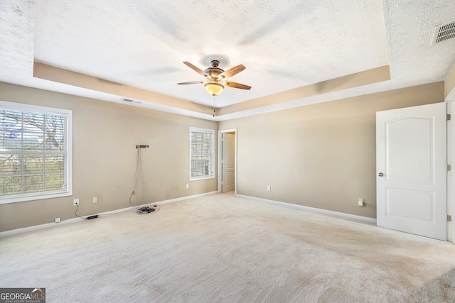 carpeted empty room featuring a tray ceiling, a textured ceiling, and ceiling fan