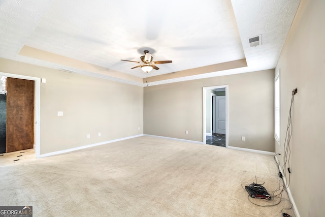 unfurnished room featuring ceiling fan, carpet floors, a raised ceiling, and a textured ceiling