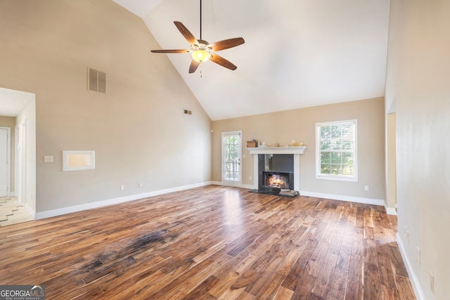 unfurnished living room with high vaulted ceiling, a wealth of natural light, ceiling fan, and hardwood / wood-style flooring