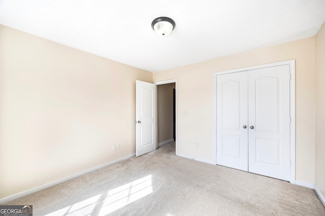 unfurnished bedroom with light carpet and a closet