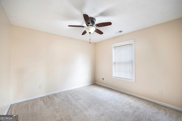 unfurnished room featuring a textured ceiling, light carpet, and ceiling fan