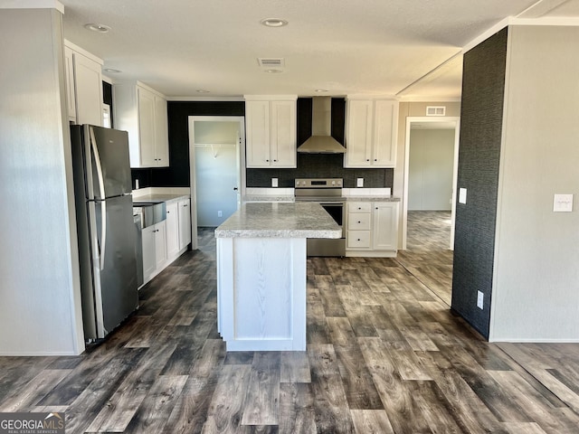 kitchen with stainless steel appliances, white cabinets, wall chimney range hood, a center island, and dark hardwood / wood-style floors