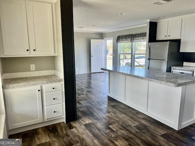 kitchen featuring stainless steel refrigerator, white cabinetry, a textured ceiling, and dark hardwood / wood-style floors