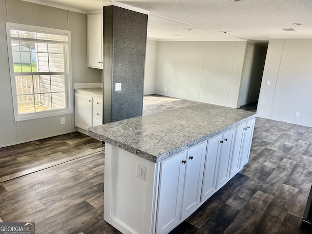 kitchen featuring dark wood-type flooring, light stone counters, a textured ceiling, and white cabinets