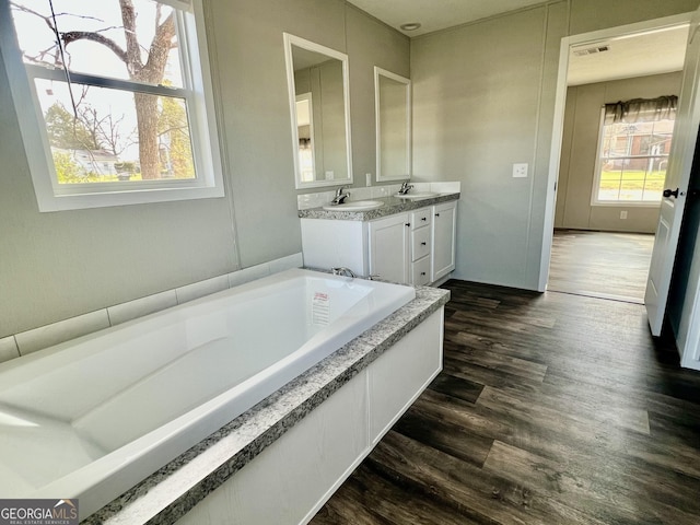 bathroom with hardwood / wood-style flooring, vanity, and a tub