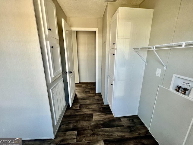 washroom featuring dark wood-type flooring, washer hookup, and a textured ceiling