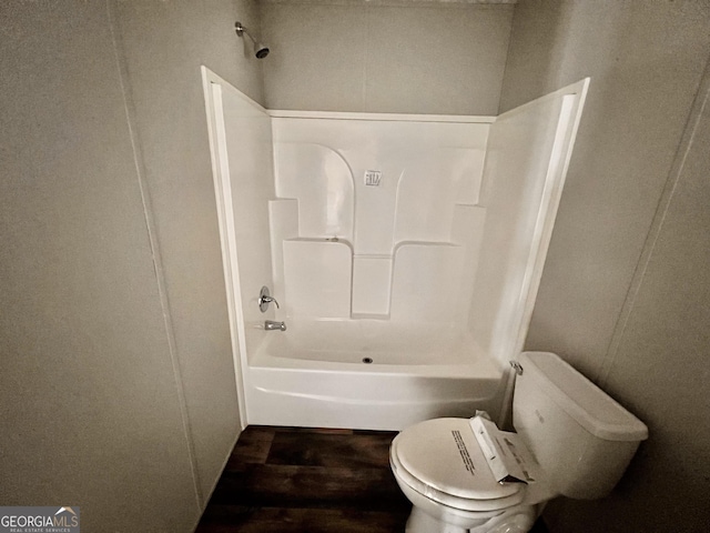 bathroom with hardwood / wood-style flooring, shower / bathing tub combination, and toilet