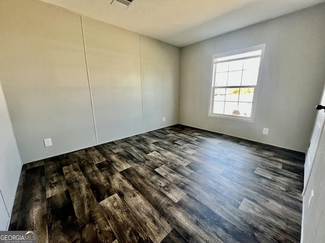 unfurnished bedroom with a textured ceiling and dark hardwood / wood-style flooring