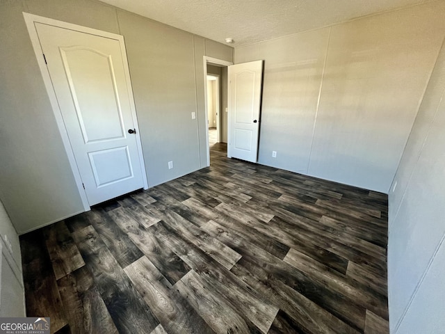 unfurnished bedroom featuring dark hardwood / wood-style floors and a textured ceiling