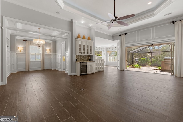 unfurnished living room with wine cooler, a tray ceiling, and ornamental molding