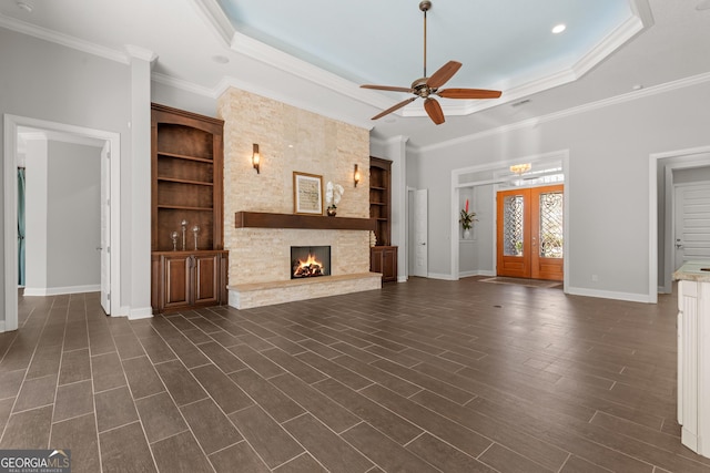 unfurnished living room with a tray ceiling, dark wood-type flooring, french doors, and a fireplace