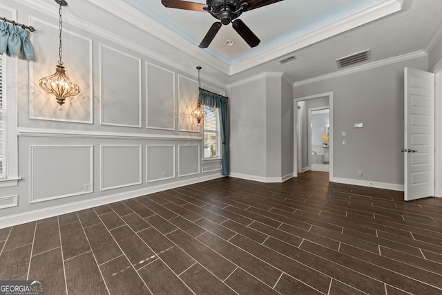 empty room with dark hardwood / wood-style flooring, ceiling fan, a raised ceiling, and crown molding