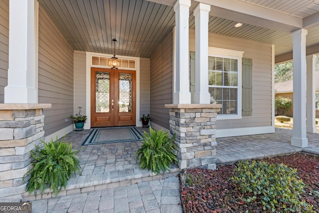 view of exterior entry featuring french doors and a porch