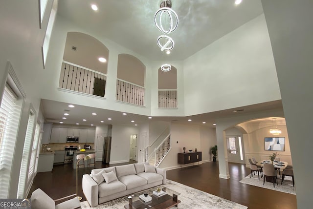 868 Still Hill Ln, Lawrenceville, GA 30045 - living area featuring arched walkways, stairs, dark wood-type flooring, a high ceiling, and recessed lighting