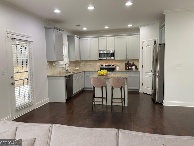 868 Still Hill Ln, Lawrenceville, GA 30045 - kitchen with appliances with stainless steel finishes, gray cabinetry, a kitchen island, dark wood-style floors, and ornamental molding