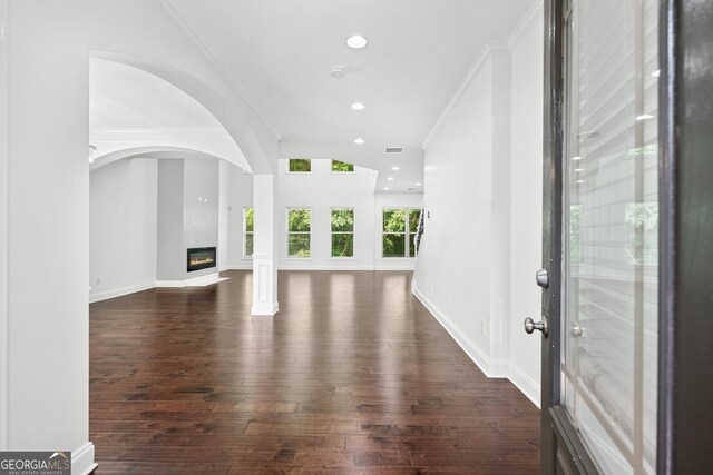 868 Still Hill Ln, Lawrenceville, GA 30045 - unfurnished living room featuring dark wood finished floors, a glass covered fireplace, recessed lighting, crown molding, and arched walkways