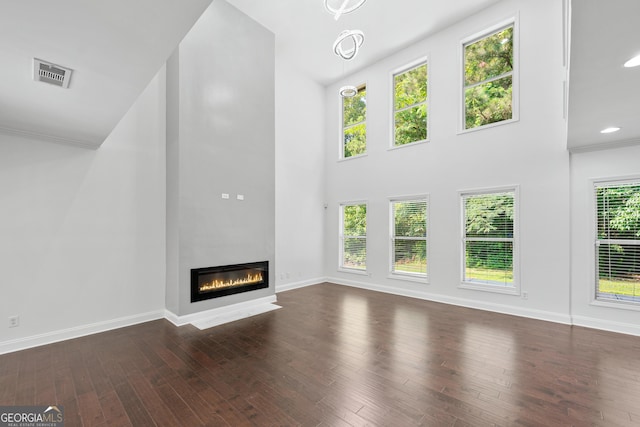 868 Still Hill Ln, Lawrenceville, GA 30045 - unfurnished living room featuring a glass covered fireplace, dark wood finished floors, a high ceiling, crown molding, and recessed lighting