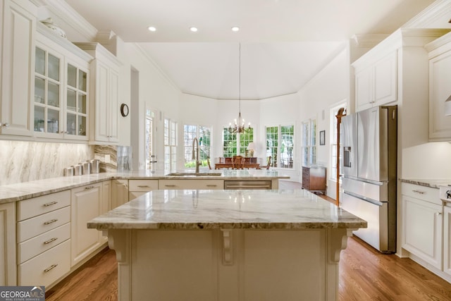 kitchen featuring stainless steel appliances, light stone countertops, pendant lighting, sink, and kitchen peninsula