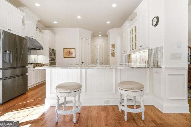 kitchen featuring white cabinetry, stainless steel fridge with ice dispenser, a breakfast bar, and kitchen peninsula