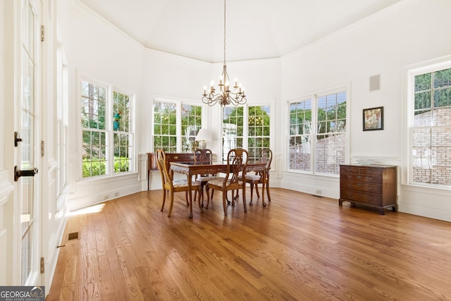 dining space with hardwood / wood-style flooring, crown molding, and a chandelier