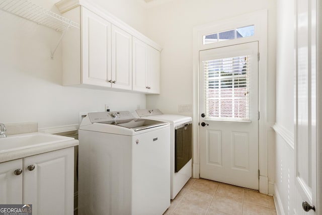 laundry area featuring sink, light tile patterned floors, independent washer and dryer, and cabinets