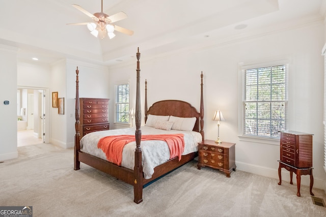 carpeted bedroom with a tray ceiling, ornamental molding, and ceiling fan