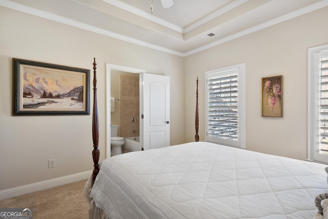 bedroom featuring a tray ceiling, ensuite bath, crown molding, and light carpet