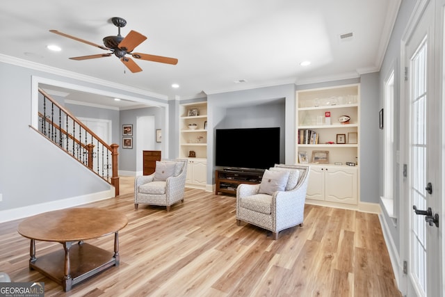 sitting room with light wood-type flooring, built in shelves, crown molding, and ceiling fan