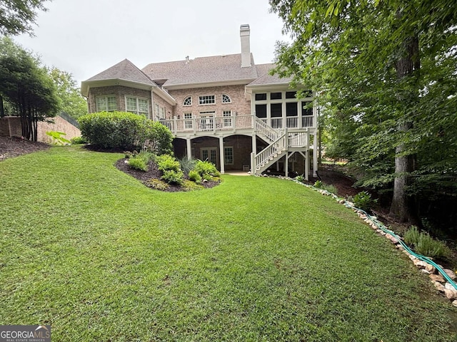 back of house with a yard, a sunroom, and a wooden deck