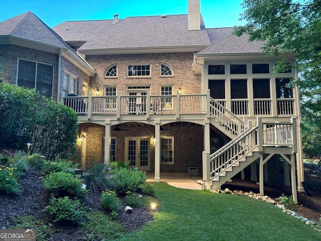 rear view of property with a lawn, a wooden deck, and a patio area