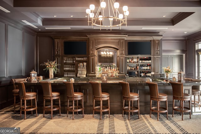 bar with a raised ceiling, a notable chandelier, and ornamental molding