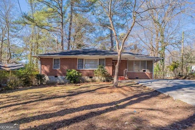 view of front of property featuring crawl space, driveway, a front lawn, and brick siding