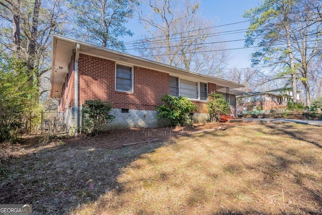 view of side of home featuring crawl space, a lawn, and brick siding