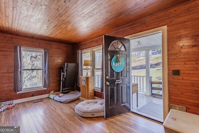 foyer featuring hardwood / wood-style floors, wooden ceiling, visible vents, and baseboards