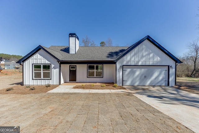 modern farmhouse with an attached garage, a shingled roof, concrete driveway, board and batten siding, and a chimney