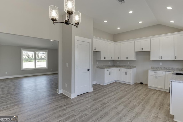 kitchen featuring decorative light fixtures, a notable chandelier, light wood-style floors, open floor plan, and white cabinetry