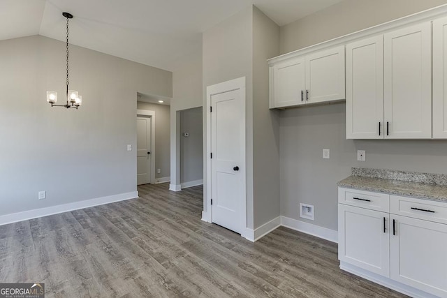 kitchen with light wood-type flooring, light stone countertops, and white cabinetry