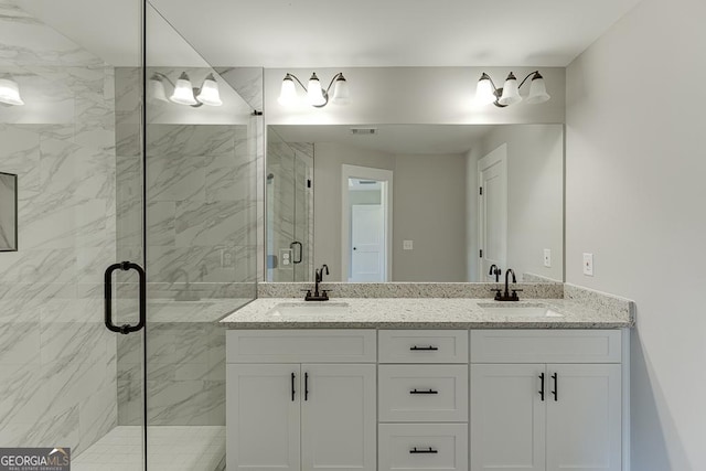 bathroom with a marble finish shower, visible vents, and a sink