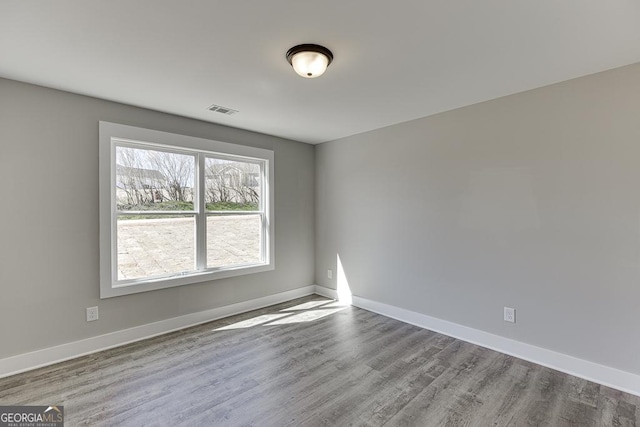 spare room featuring light wood-style floors, visible vents, and baseboards