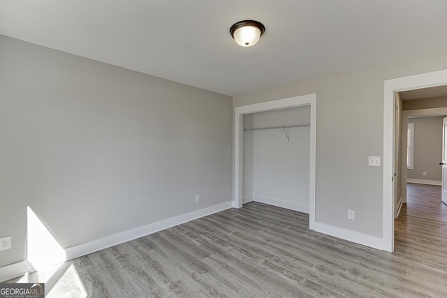 unfurnished bedroom with light wood-style floors, baseboards, and a closet