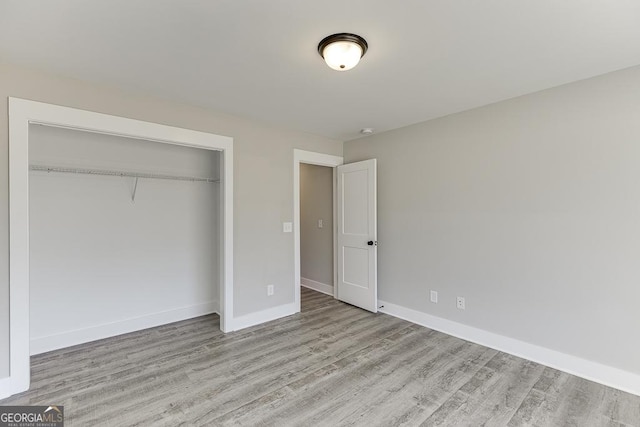 unfurnished bedroom with light wood finished floors, a closet, and baseboards