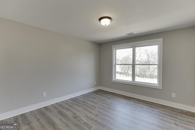 empty room with light wood-type flooring, visible vents, and baseboards