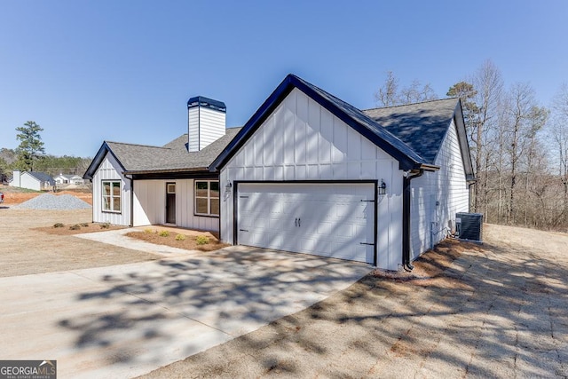 modern inspired farmhouse featuring a garage, concrete driveway, a chimney, cooling unit, and board and batten siding