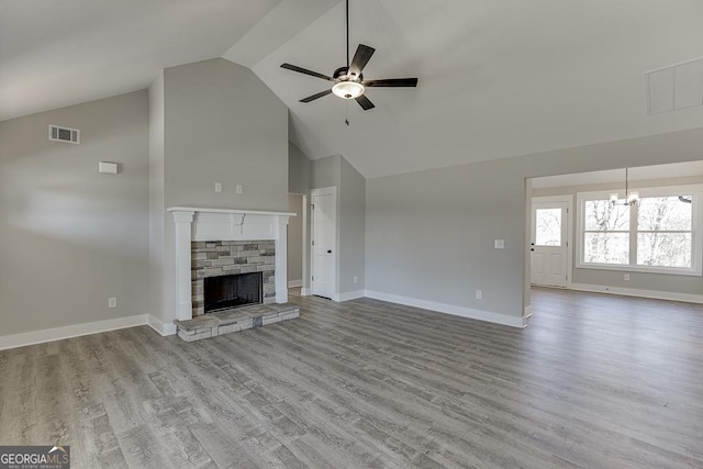 unfurnished living room featuring light wood-type flooring, a fireplace, visible vents, and ceiling fan with notable chandelier