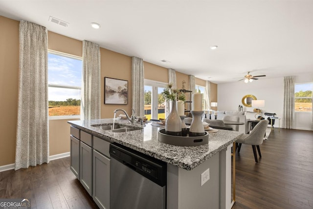 kitchen featuring gray cabinetry, an island with sink, light stone countertops, stainless steel dishwasher, and sink