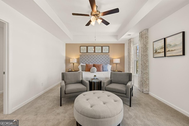 carpeted bedroom with ceiling fan and a tray ceiling