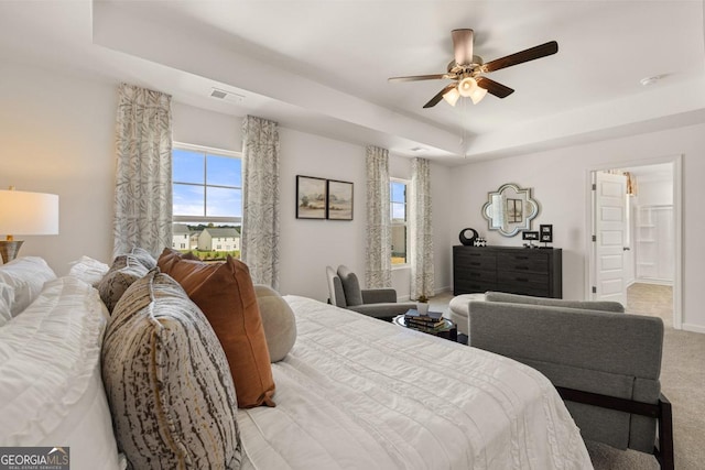 carpeted bedroom with a tray ceiling and ceiling fan