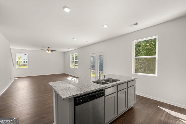 kitchen featuring a center island with sink, sink, light stone counters, dishwasher, and gray cabinetry