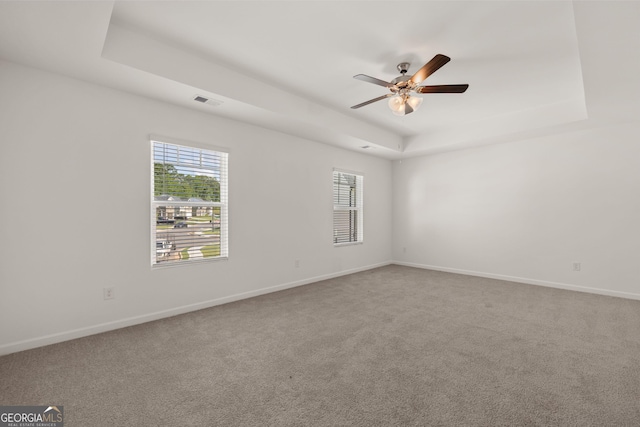 carpeted empty room with a tray ceiling and ceiling fan